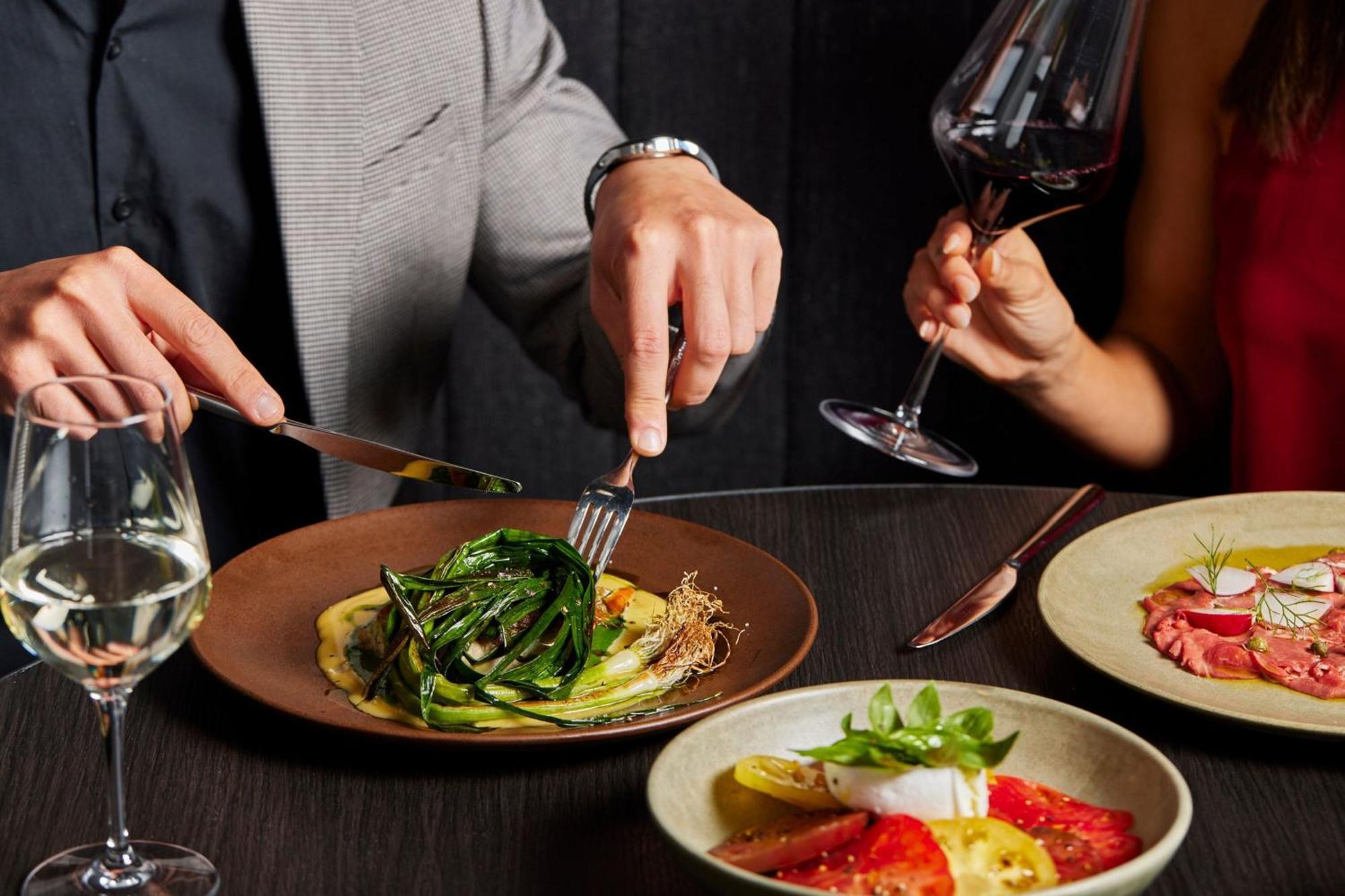 Melbourne Marriott Hotel Docklands Exterior photo A man using a knife and fork to cut into a meal